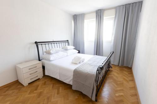 a bedroom with a white bed and a wooden floor at Apartment Srecko in Omiš