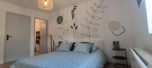 - une chambre dotée d'un lit avec des draps bleus et des plantes sur le mur dans l'établissement Avignon Intramuros - Appartement Le 36, à Avignon