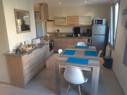 - une cuisine avec une table en bois et des chaises blanches dans l'établissement Hameau Provençal - T2 NEUF très calme tout à pied prestation +++, à Six-Fours-les-Plages