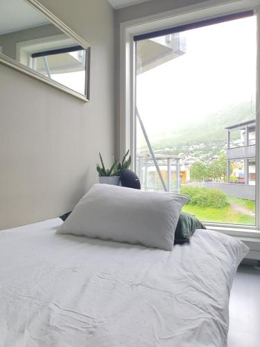 um quarto com uma cama branca e uma grande janela em Northern Dreams Apartment with free parking em Tromsø