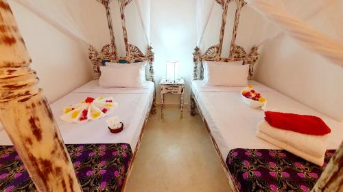 two beds in a room with white sheets at Lalasalama B&B in Watamu