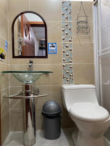 a bathroom with a toilet and a sink and a mirror at Hostal Arauco in Otavalo