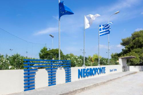 a blue bench in front of a wall with three flags at Negroponte Resort Eretria in Eretria
