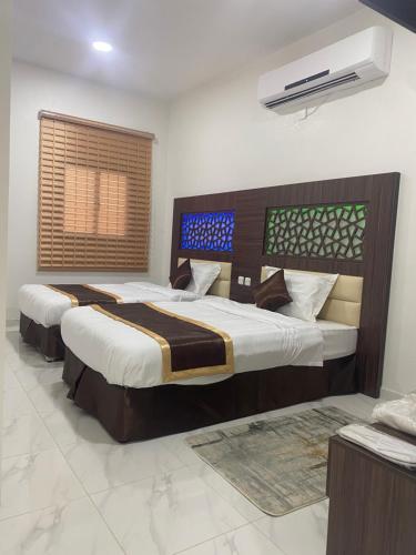 1 dormitorio con 2 camas y ventana en Wind alula en Al Ula