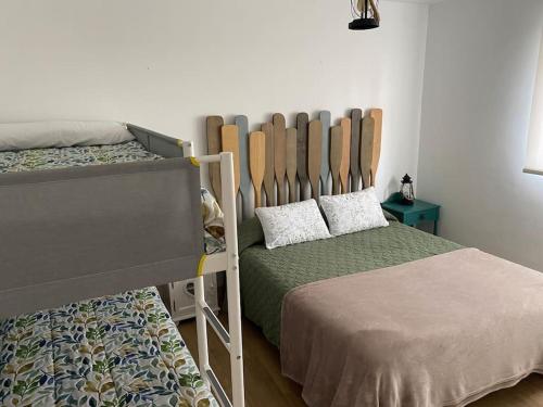 a bedroom with two bunk beds and a bed with a headboard at Preciosa casa con jardín en Oriñon in Oriñón