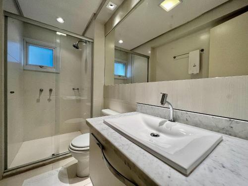 La salle de bains est pourvue d'un lavabo, d'une douche et de toilettes. dans l'établissement Condado Di Merano 3 dorm Centro by Achei Gramado, à Gramado