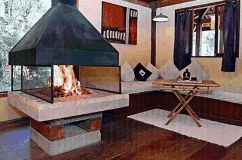 a living room with a fireplace and a table at Residencial Warabi in Visconde De Maua