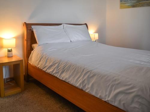 un lit avec des draps blancs et deux lampes sur des tables dans l'établissement Flint House, à Sheringham