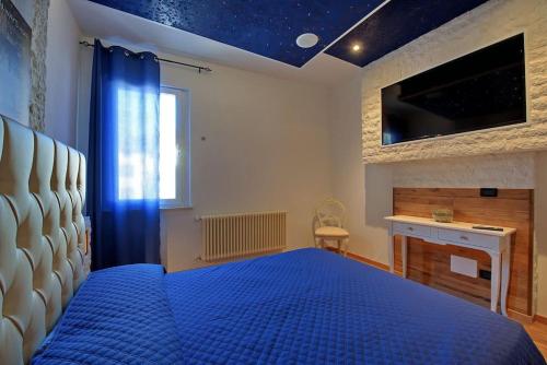 sypialnia z niebieskim łóżkiem i telewizorem w obiekcie Vicolo Mincio Home w mieście Salionze