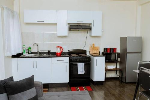 a kitchen with white cabinets and a black stove at Kunyumba Luxury Homes in Lusaka