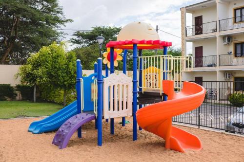 a playground with colorful slides in front of a building at Kunyumba Luxury Homes in Lusaka