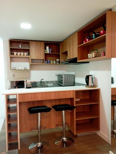 una cocina con barra y 2 taburetes en Hermoso Monoambriente ZV308, Edificio Zetta Village Airport, en Asunción