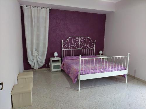 una camera con un letto bianco e una parete viola di Casa Marina a Linguaglossa