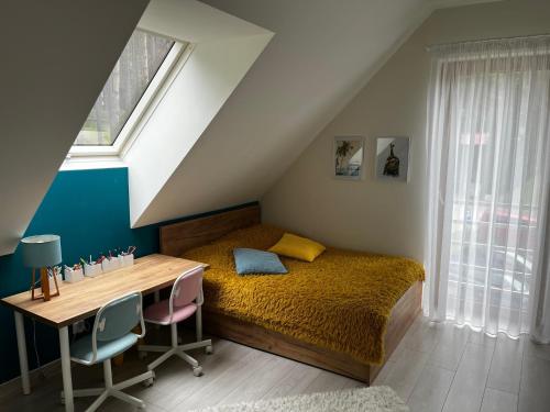 a bedroom with a bed and a desk and a window at Villa Toscana in Gietrzwałd