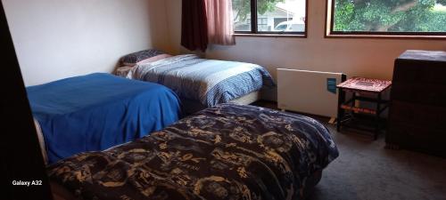 a room with two beds and a table and a window at City Bungalow in Tauranga