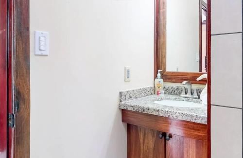 a bathroom with a sink and a mirror at Sandy Feet Beach Resort in Placencia Village