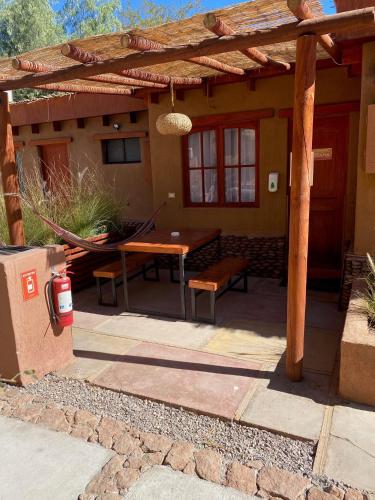 a patio with a table and a wooden pergola at Tambo Atacama Lodge in San Pedro de Atacama