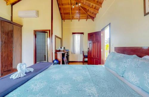 a bedroom with a large bed with a blue comforter at Sandy Feet Beach Resort in Placencia Village