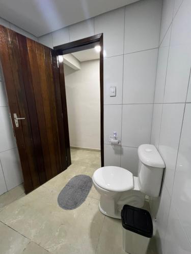 ein Badezimmer mit einem WC und einer Holztür in der Unterkunft Acomodação aconchegante próximo ao centro in Garanhuns