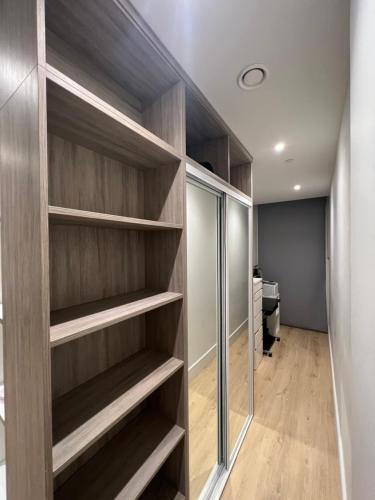 um closet com prateleiras de madeira em London LuXXe Suites & Apartments - London Heathrow Airport, Terminal 1 2 3 4 5 em New Bedfont
