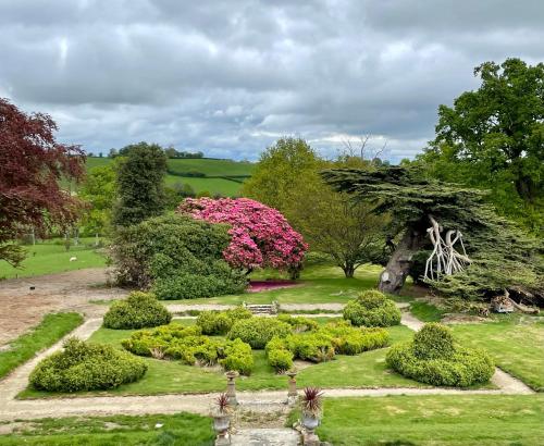 einen Garten mit rosa Blumen und einem Baum in der Unterkunft Llanerchydol Hall Suites in Welshpool