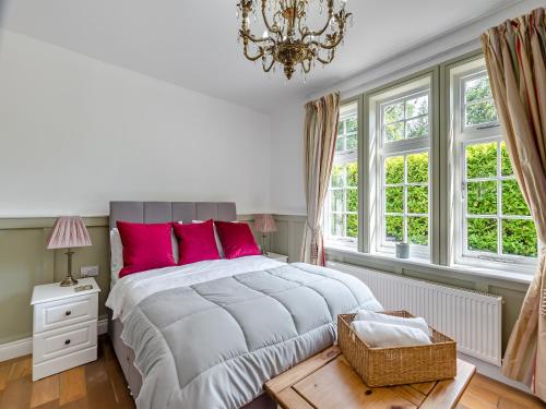 una camera da letto con un letto con cuscini rosa e un lampadario a braccio di Bridgegate House a Belper