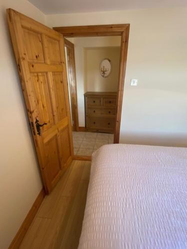 a bedroom with a bed and a wooden door at JMD Lodge - Self Catering Property in the heart of The Burren between Ballyvaughan, Lisdoonvarna, Doolin and Kilfenora in County Clare Ireland in Ballyvaughan