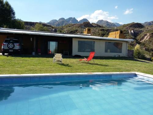 a swimming pool with two chairs and a house at Kairos Cabañas in Las Compuertas