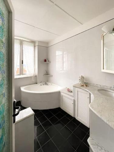 a white bathroom with a tub and a sink at Tra Cielo e Mare in Follonica