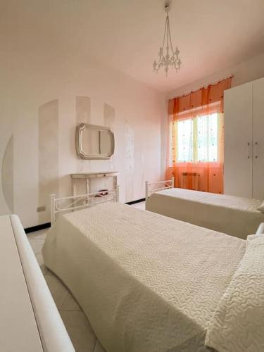 a white bedroom with two beds and a window at Tra Cielo e Mare in Follonica