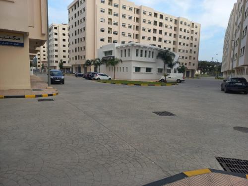 un aparcamiento con coches estacionados frente a los edificios en Rawan Appart en Tánger