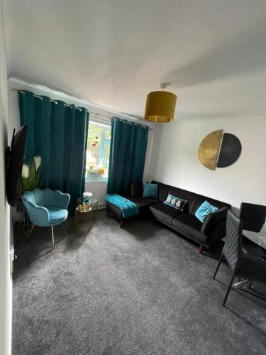 a living room with a black couch and a blue chair at Large Stylish 2 Bedroom Apartment Stevenage Sleep 6 in Stevenage