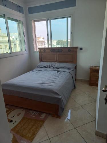 a bedroom with a bed and two windows at Rawan Appart in Tangier