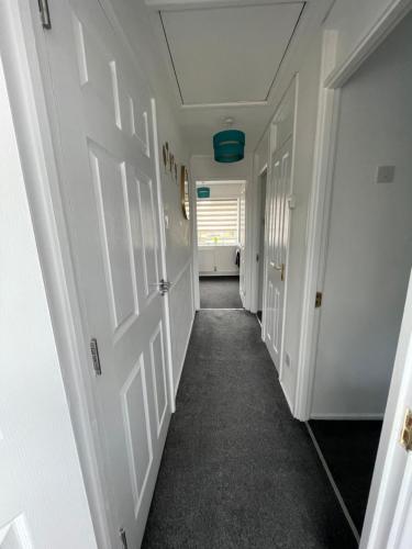 a hallway with white doors and a room with a window at Large Stylish 2 Bedroom Apartment Stevenage Sleep 6 in Stevenage