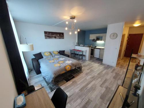 a bedroom with a bed and a table and a kitchen at Appartement équipé proche aéroport et gare in Beauvais