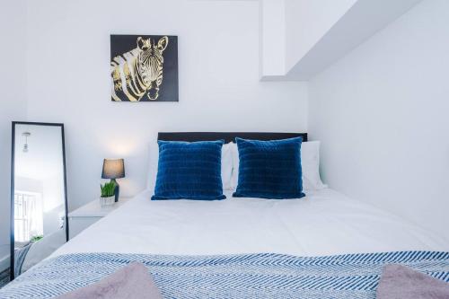 ein Schlafzimmer mit einem weißen Bett mit blauen Kissen in der Unterkunft Beautiful apartment DOS in Litherland