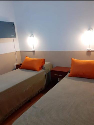 2 camas en una habitación con 2 almohadas de color naranja en Departamento Celsa en Salta