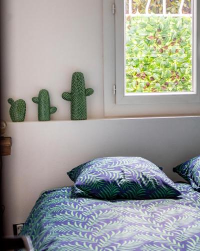 a bedroom with a bed and a window with cactuses at Endoume Notre Dame de la Garde T2 avec PARKING in Marseille