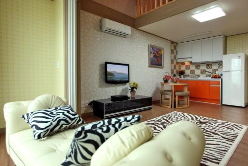 a living room with a white couch and a kitchen at Capri Hakdong Pension in Geoje 