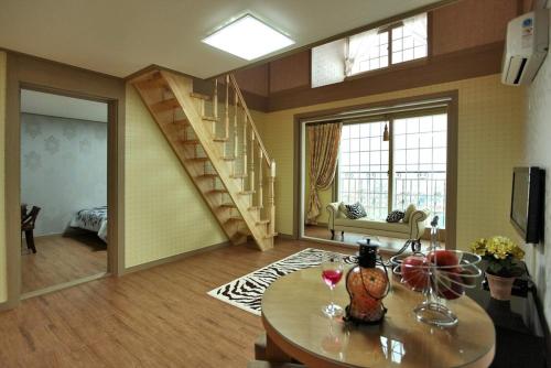 a living room with a table and a staircase at Capri Hakdong Pension in Geoje 