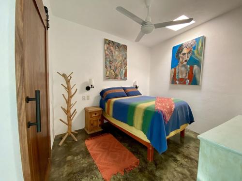 1 dormitorio con 1 cama y una pintura en la pared en Casita del Artista, en San Patricio Melaque