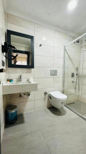 a bathroom with a toilet and a sink and a shower at Rosella Royal Suit - روزيلا رويال in Arsin