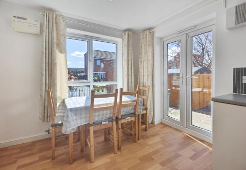 a dining room with a table and chairs and windows at The Metcombe - Bright Townhouse 5 Minutes To Manchester City Centre With Free Parking in Manchester