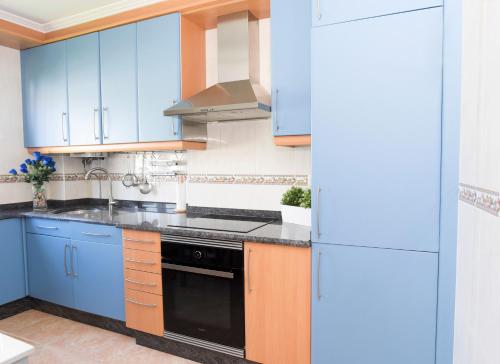 een keuken met blauwe kasten en een zwarte kachel bij VelayLi - Apartamento en el centro de Finisterre in Finisterre