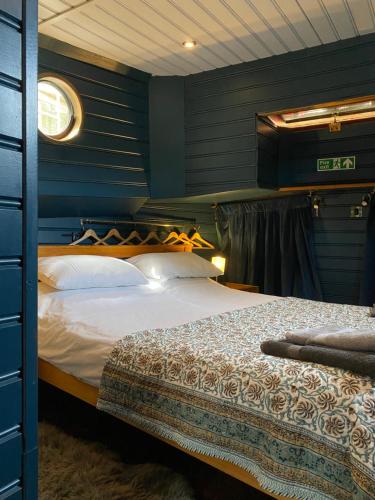 a bedroom with a bed with blue walls at Dutch Barge, Fisherman's Wharf, Sandwich in Sandwich