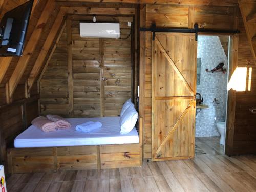 a small bed in a wooden room with a bathroom at RECANTO VERDES VALES in Palhoça