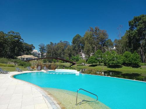 a large blue swimming pool with a bridge over it at Green Park in Punta del Este