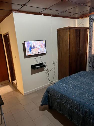a bedroom with a bed and a tv on the wall at Studio meublé à Conakry in Conakry