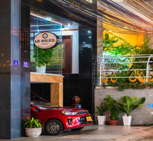 a red car is parked outside of a building at LE SOLEIL HOTEL managed by NEST Group in Nha Trang