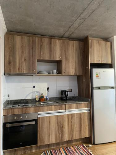 - une cuisine avec des placards en bois et un réfrigérateur blanc dans l'établissement Sur de chile, à Temuco